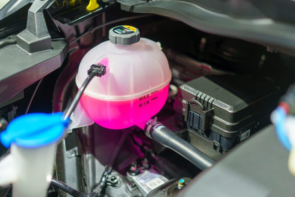 close-up of the coolant tank containing vibrant pink antifreeze. This essential component ensures optimal temperature regulation, safeguarding your vehicle's engine against overheating and maintaining peak performance on the road